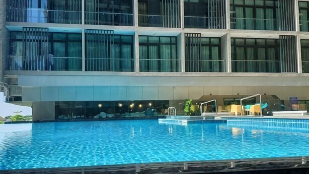 A modern hotel with a swimming pool, large windows, and a multi-story structure. - Aj suites @ Riverson SOHO (Kota Kinabalu)