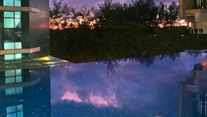 A modern building with a reflective pool, clear skies, and distant trees. - Aj suites @ Riverson SOHO (Kota Kinabalu)