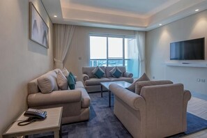 Ein modernes Wohnzimmer mit einer Sofagarnitur, einem Couchtisch und einem flachbildfernseher an der Wand.
