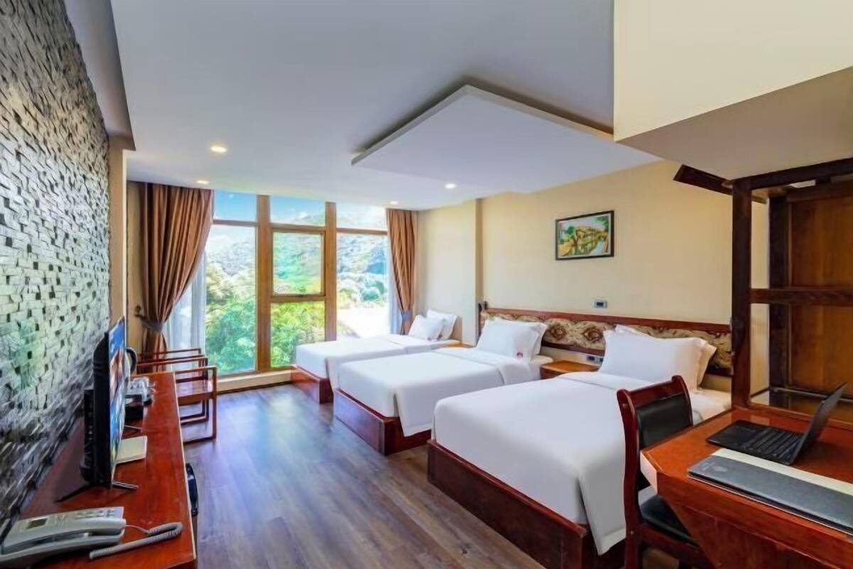 Une chambre d’hôtel avec deux lits, un bureau avec un ordinateur portable, une télévision et un téléphone.