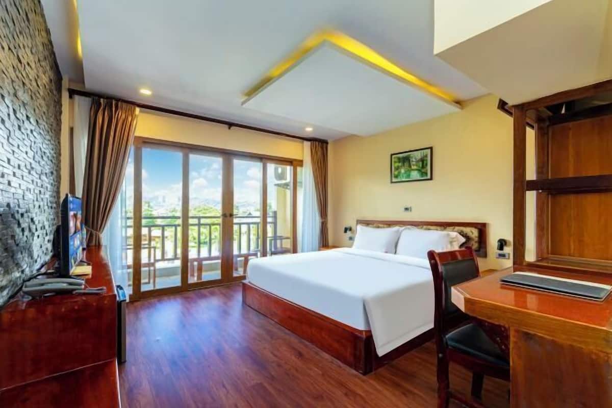 Une chambre d’hôtel avec un grand lit, un bureau, une chaise, une télévision et un balcon avec vue.