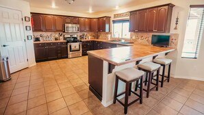 Una cocina moderna con armarios de madera oscura, una isla grande con taburetes de bar, un horno de acero inoxidable y un microondas.