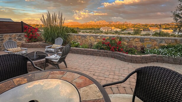 Un patio al aire libre con pared de piedra, una mesa redonda y dos sillas.