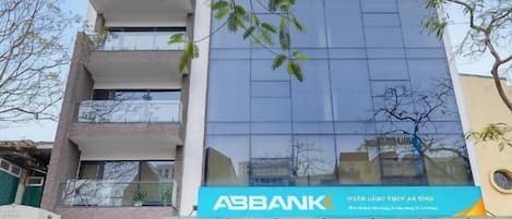 A multi-story building with a modern glass facade, a prominent ASBANK sign, and a visible entrance with a staircase leading to the ground floor.