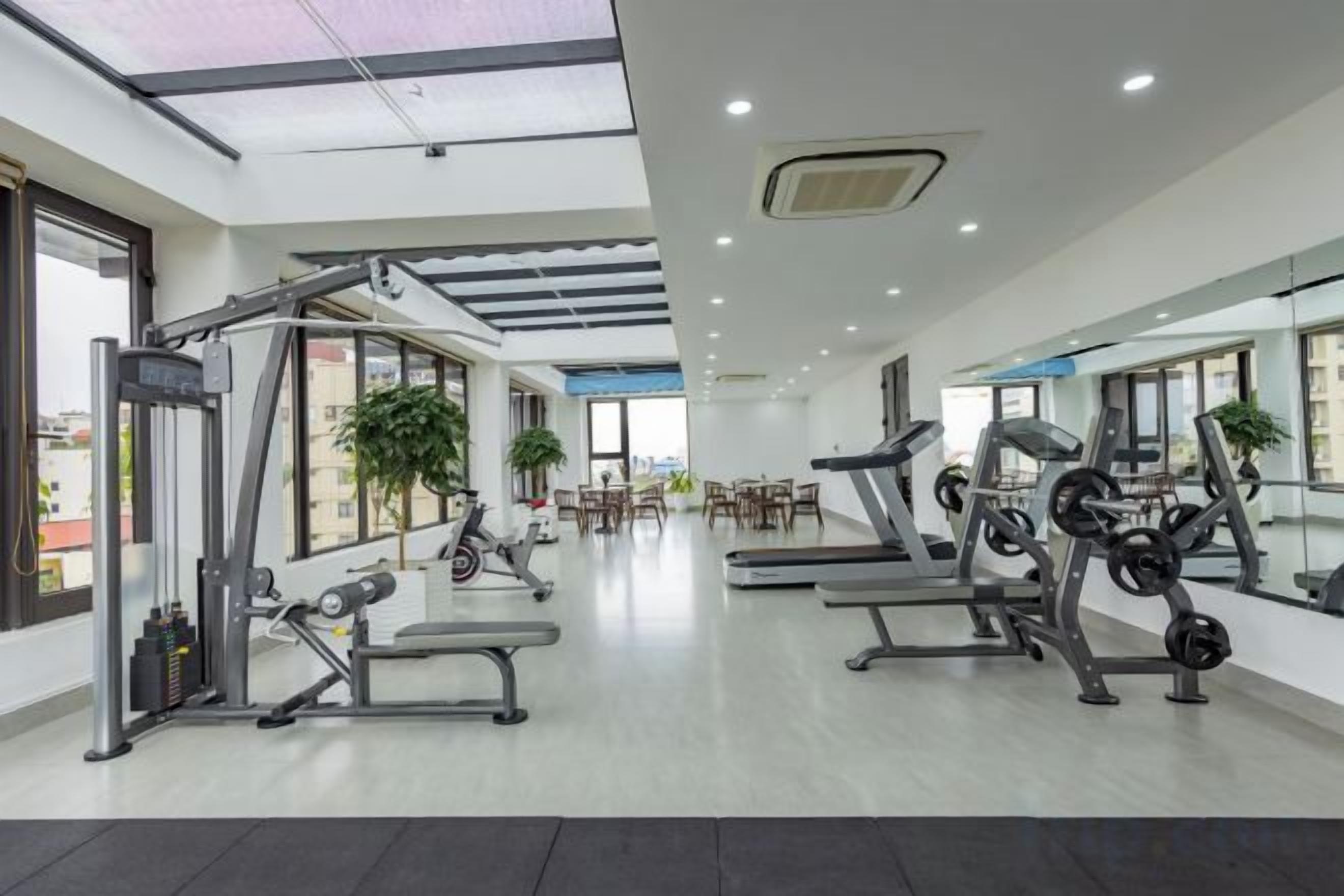 A gym with cardio machines, weightlifting equipment, and a mirrored wall.