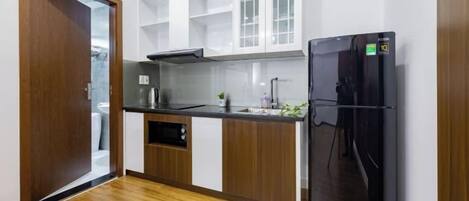 A compact kitchen with a black refrigerator, wooden cabinets, and a white countertop.