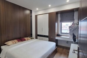 A bedroom with a bed, wardrobe, and a window with a view. - Phong Lan Building and Apartments (Haiphong)
