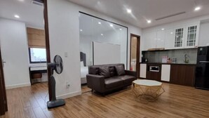 Ein modernes Wohnzimmer mit einer Couch, einem kleinen runden Tisch und einem Standventilator.