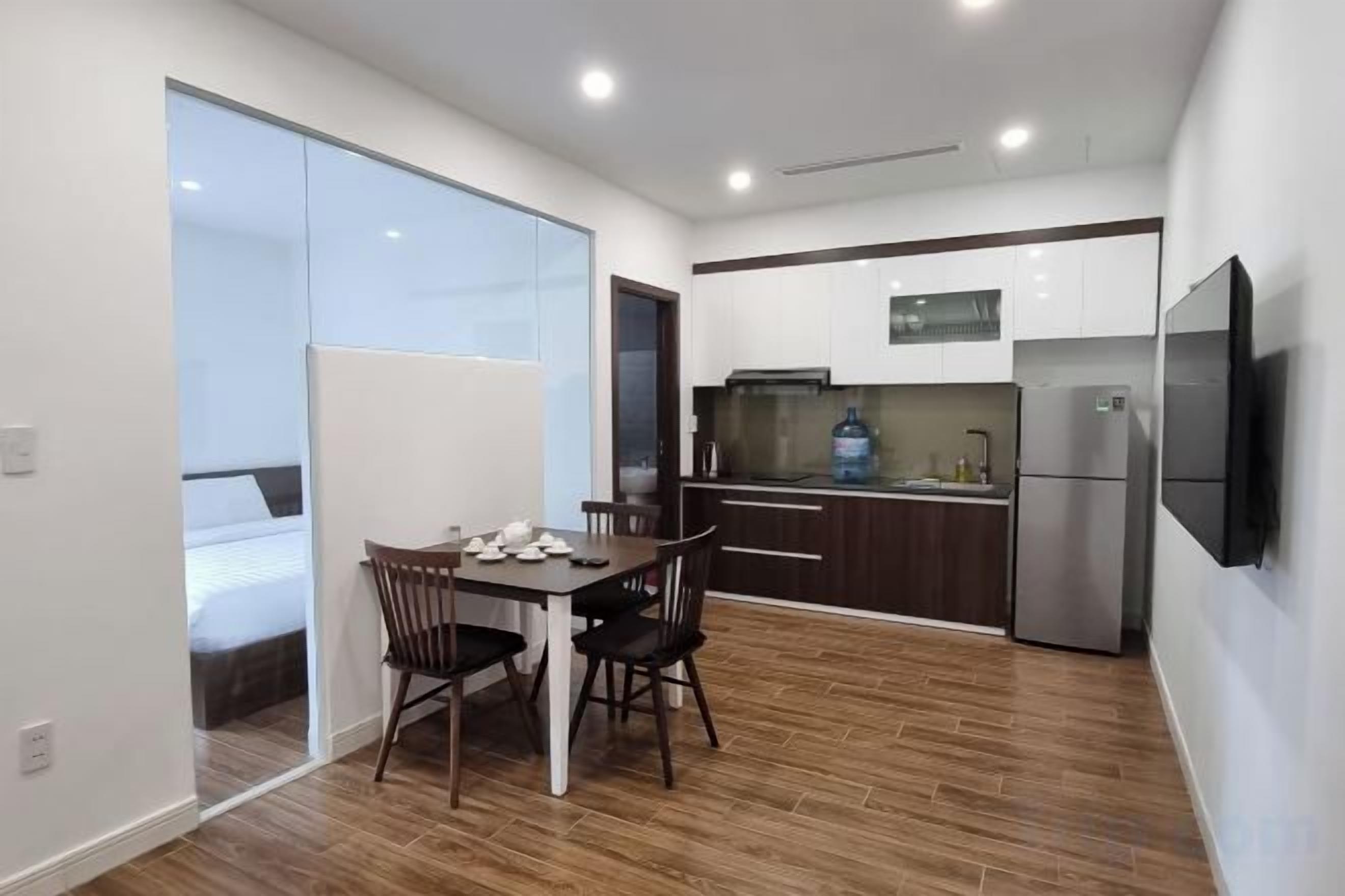 A compact kitchen with a dining area, a refrigerator, and a flat-screen TV.
