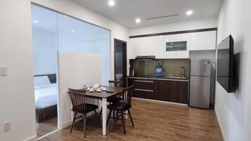 A compact kitchen with a dining area, a refrigerator, and a flat-screen TV.