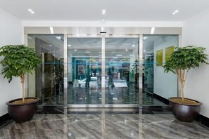 A modern entrance with glass doors, potted plants, and a marble floor. - Phong Lan Building and Apartments (Haiphong)