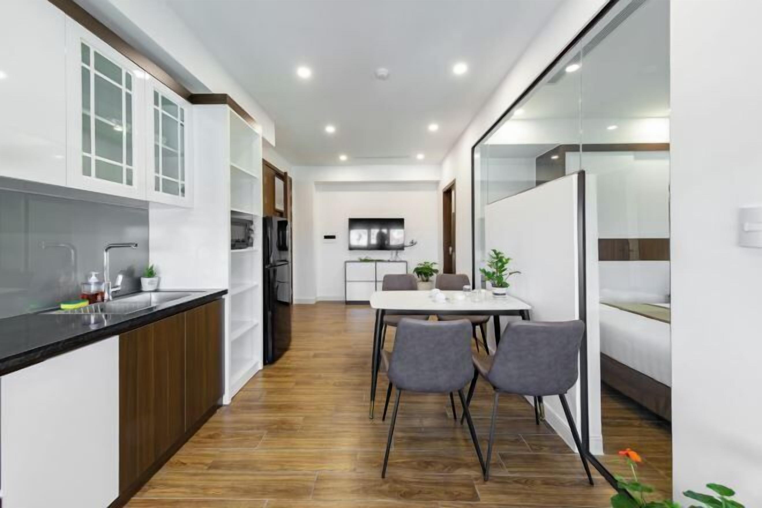 Uma cozinha moderna com armários brancos, bancada preta e área de refeições com mesa e cadeiras.