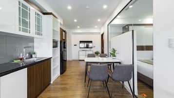 Uma cozinha moderna com armários brancos, bancada preta e área de refeições com mesa e cadeiras.