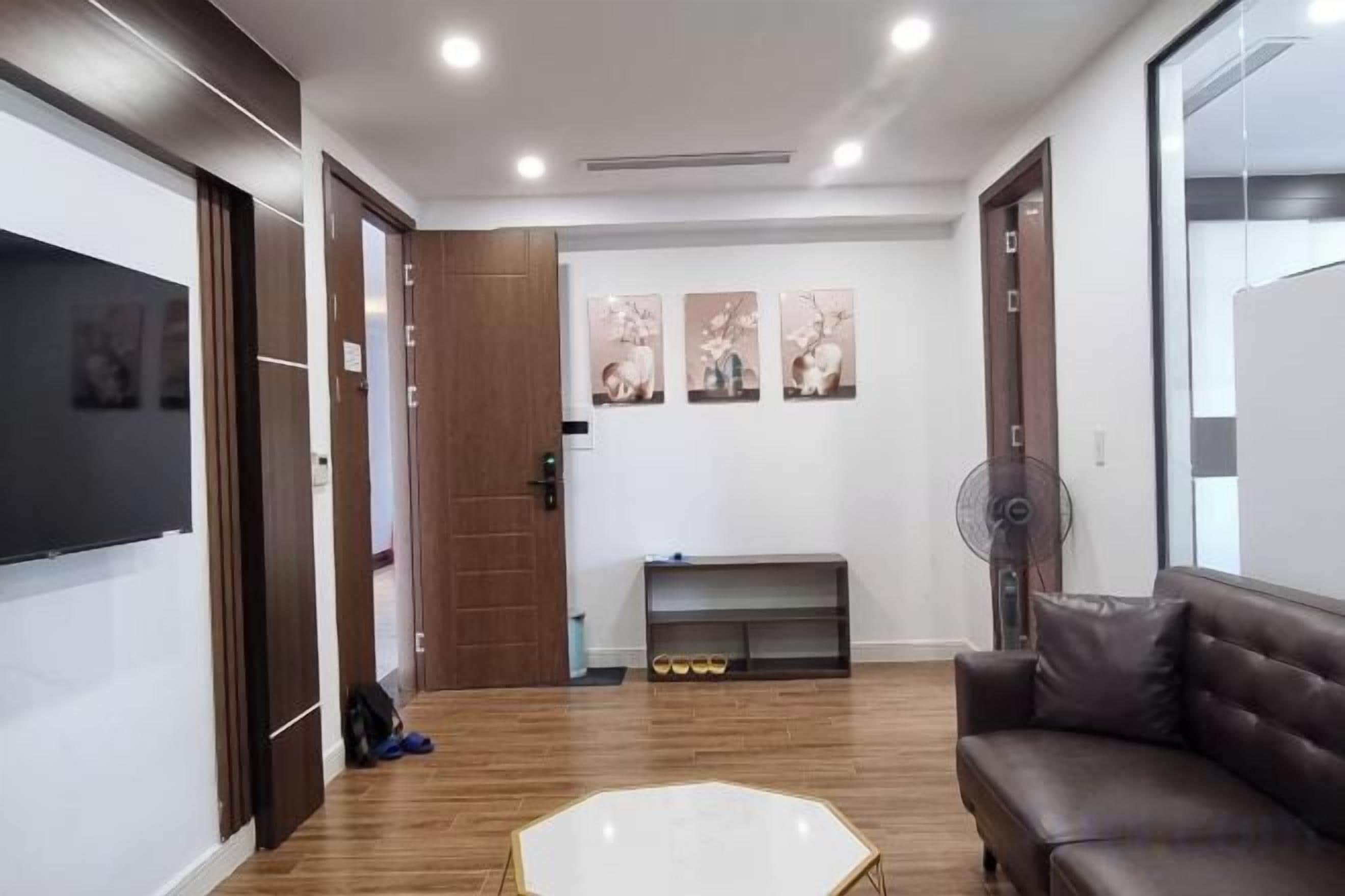 A modern living room with a wooden floor, a white coffee table, a brown sofa, and a fireplace.