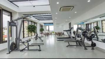Uma academia moderna com equipamentos de cardio, estações de musculação e um amplo espelho.