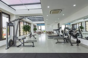 Ein modernes Fitnessstudio mit Cardiogeräten, Gewichtecken und einer großen Spiegelwand.