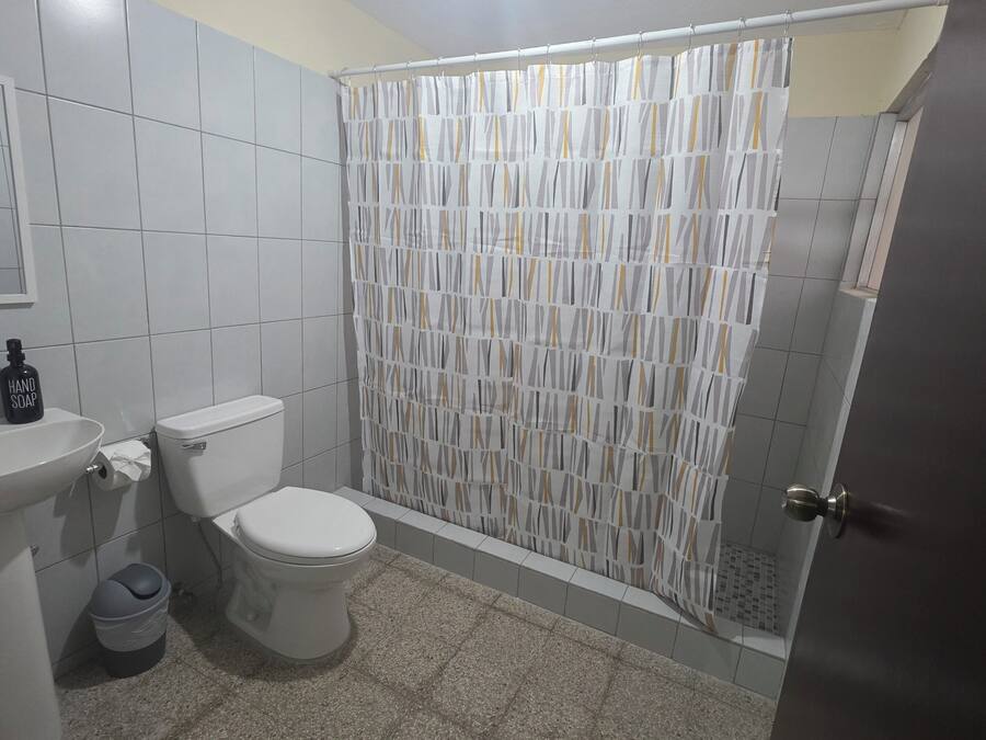 A bathroom with a toilet, sink, and shower curtain.