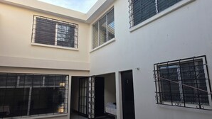 A multi-level residential building with multiple windows, each secured with metal bars. - Be happy hotel Gt (Guatemala City)