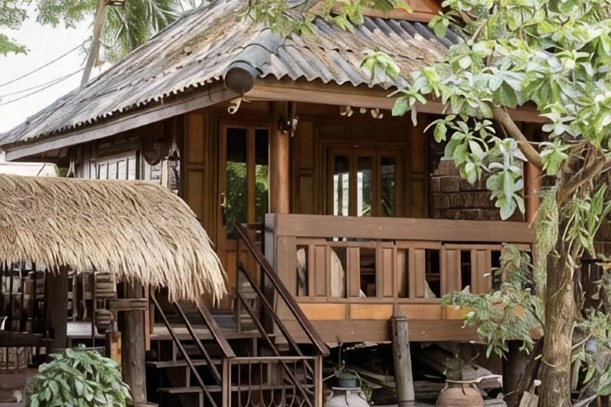 A wooden house with a thatched roof, a wooden staircase, and a porch.