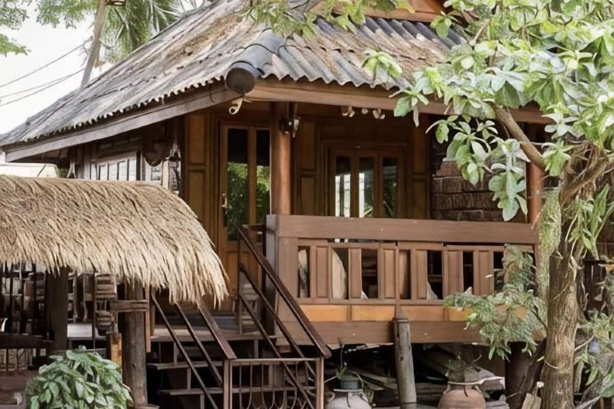 A wooden house with a thatched roof, a wooden staircase, and a porch.