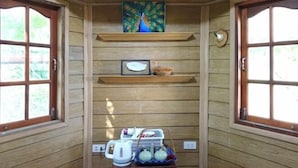 A wooden interior with a peacock painting, a framed picture, and a kettle on a shelf. - Sunny Stone Villa (Bangkok)