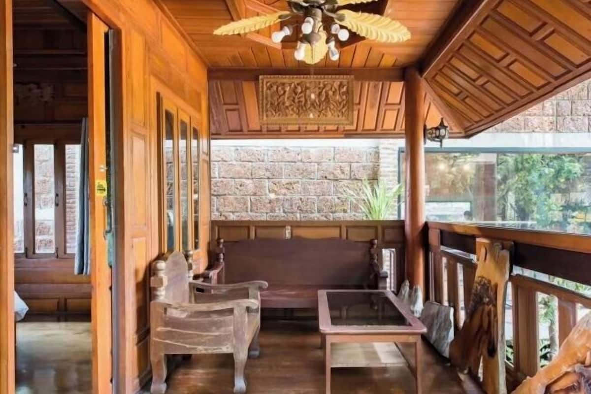A wooden interior with a bench, a table, and a stone wall.