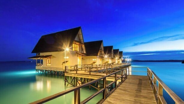 Overwater bungalows connected by a wooden deck. - Sienna Resort (Maratua)
