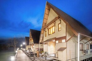 A hotel with a wooden exterior, a covered outdoor area with tables, and a dock extending into the water. - Sienna Resort (Maratua)