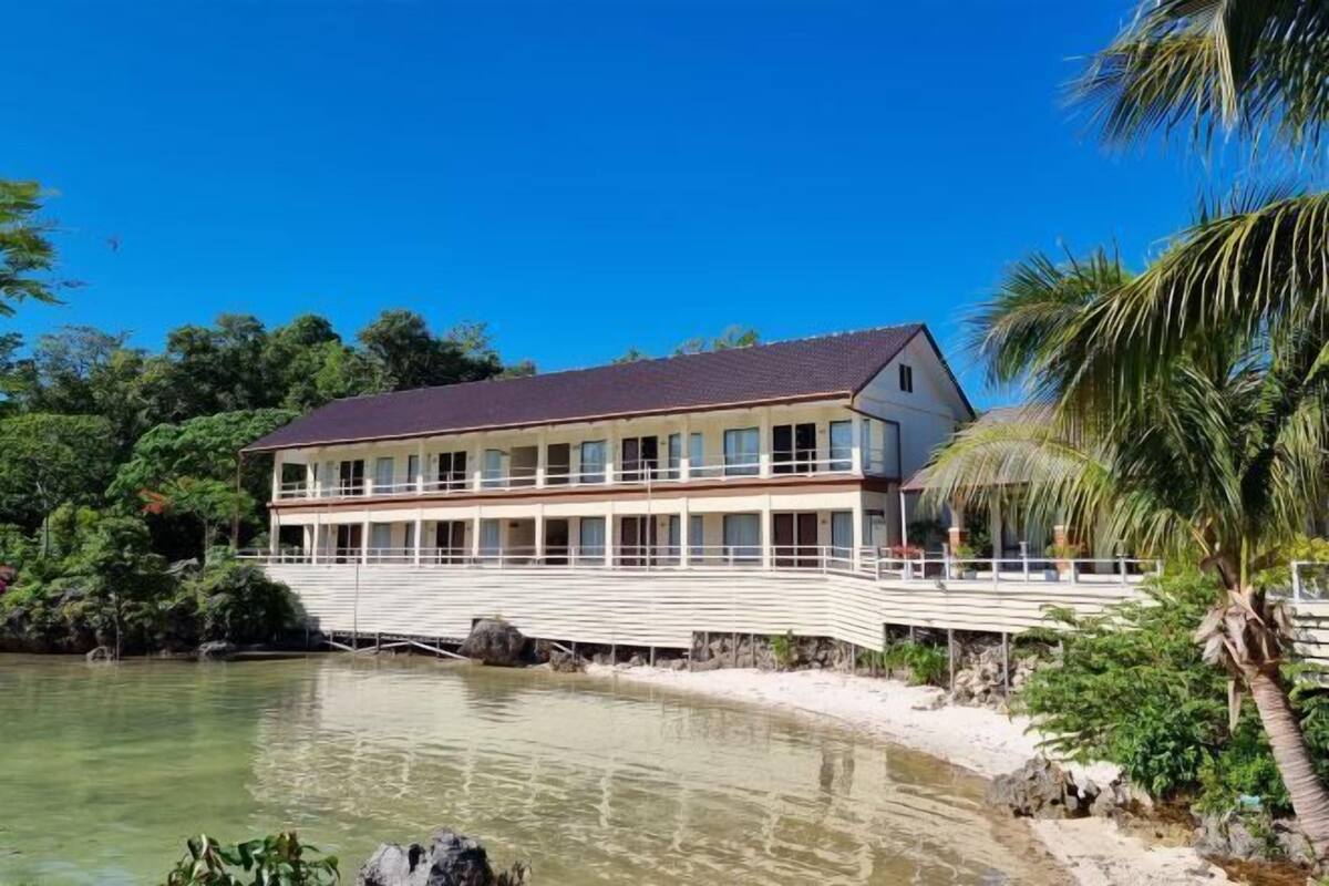 A waterfront hotel with a balcony, a pool, and a view of the water.
