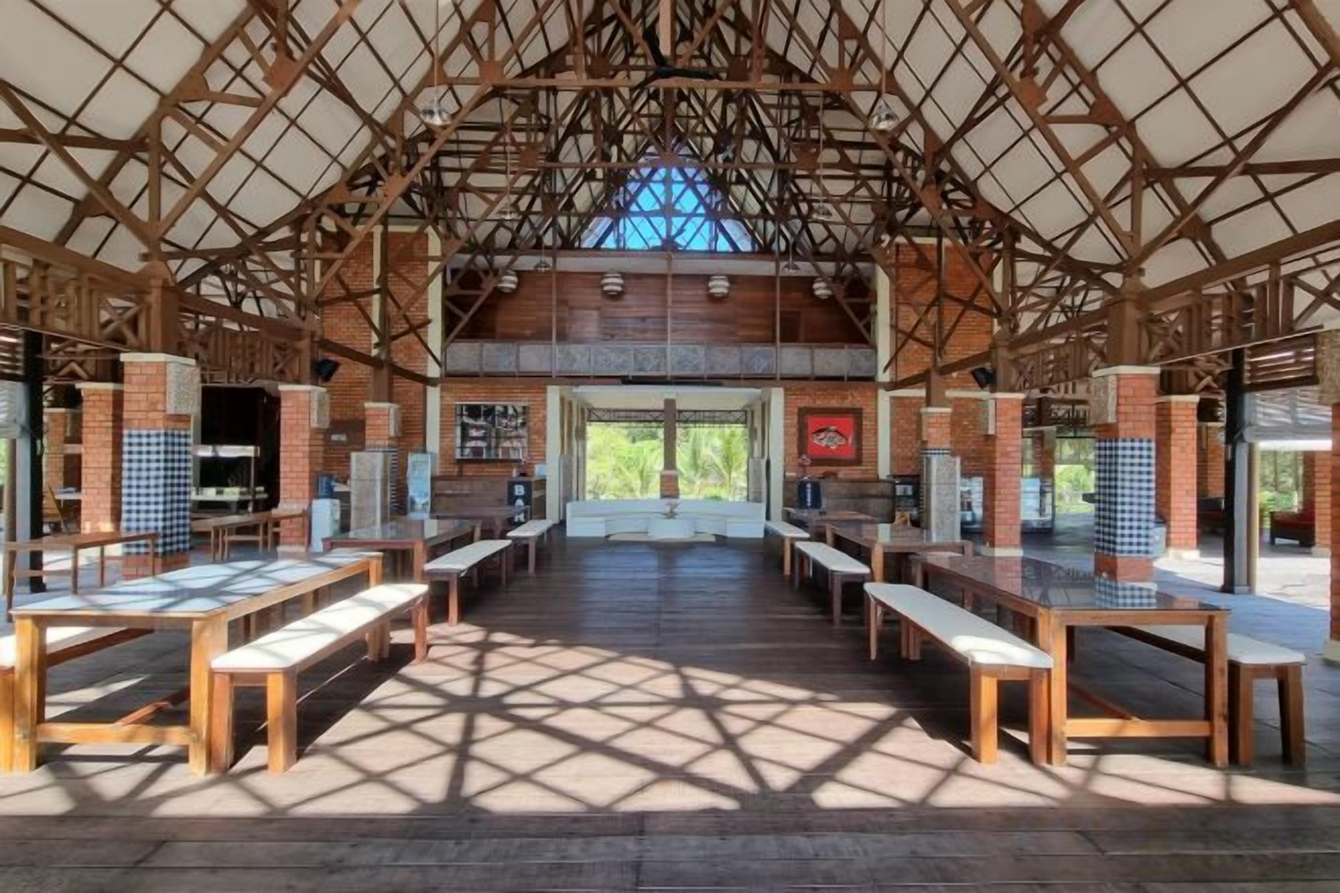 An indoor space with a high ceiling, wooden beams, and a central open area with benches and tables.
