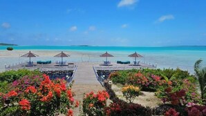 A wooden pier leading to a beach with lounge chairs and umbrellas. - Sienna Resort (Maratua)