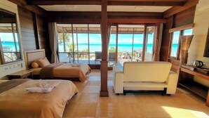 A room with two beds, a sofa, and large windows with a view of the ocean. - Sienna Resort (Maratua)