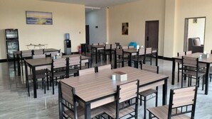 Une pièce spacieuse avec plusieurs tables et chaises, un distributeur d’eau et un tableau accroché au mur.