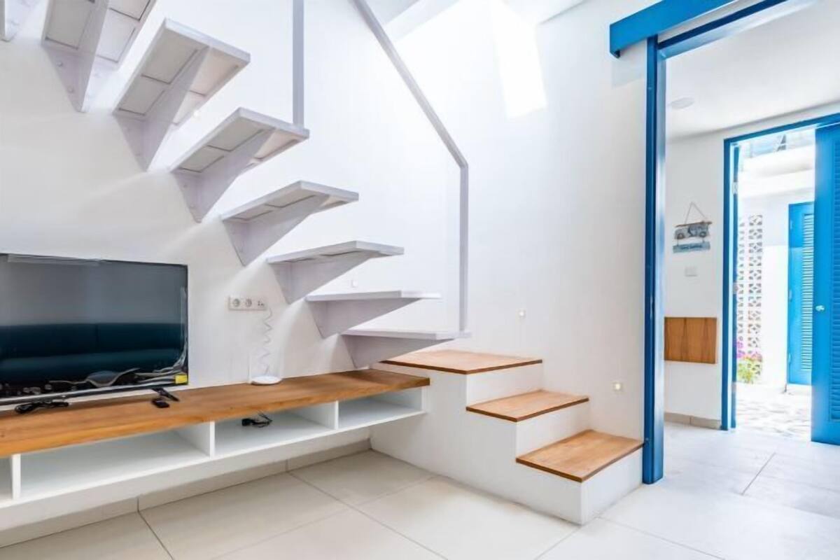Un interior moderno con una escalera, un televisor de pantalla plana y una puerta azul.