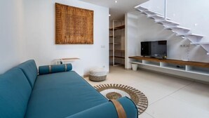 Ein modernes Wohnzimmer mit einer Couch, einem Fernseher und einer Treppe.