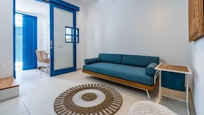 Ein modernes Wohnzimmer mit einem salbeengrünfarbenen Sofa, einem Holztisch und einem großen Fenster.