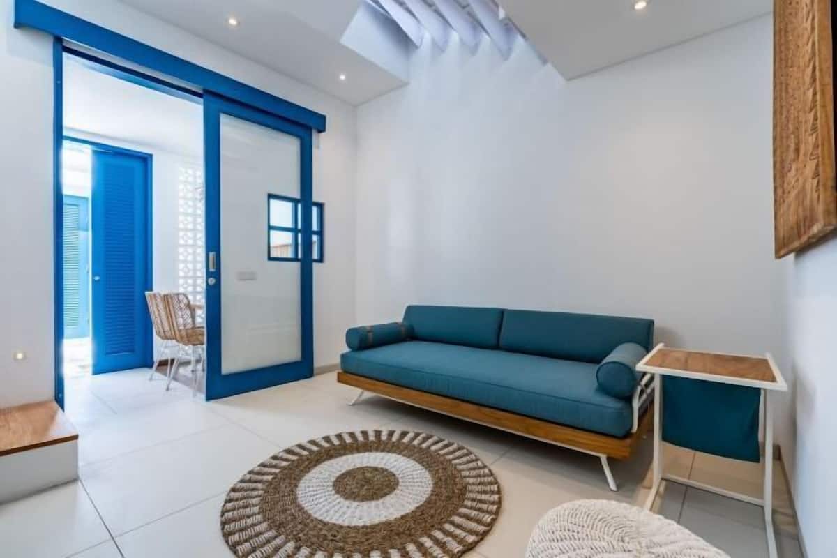 Una sala de estar moderna con un sofá color turquesa, una mesa de centro de madera y un ventanal grande.