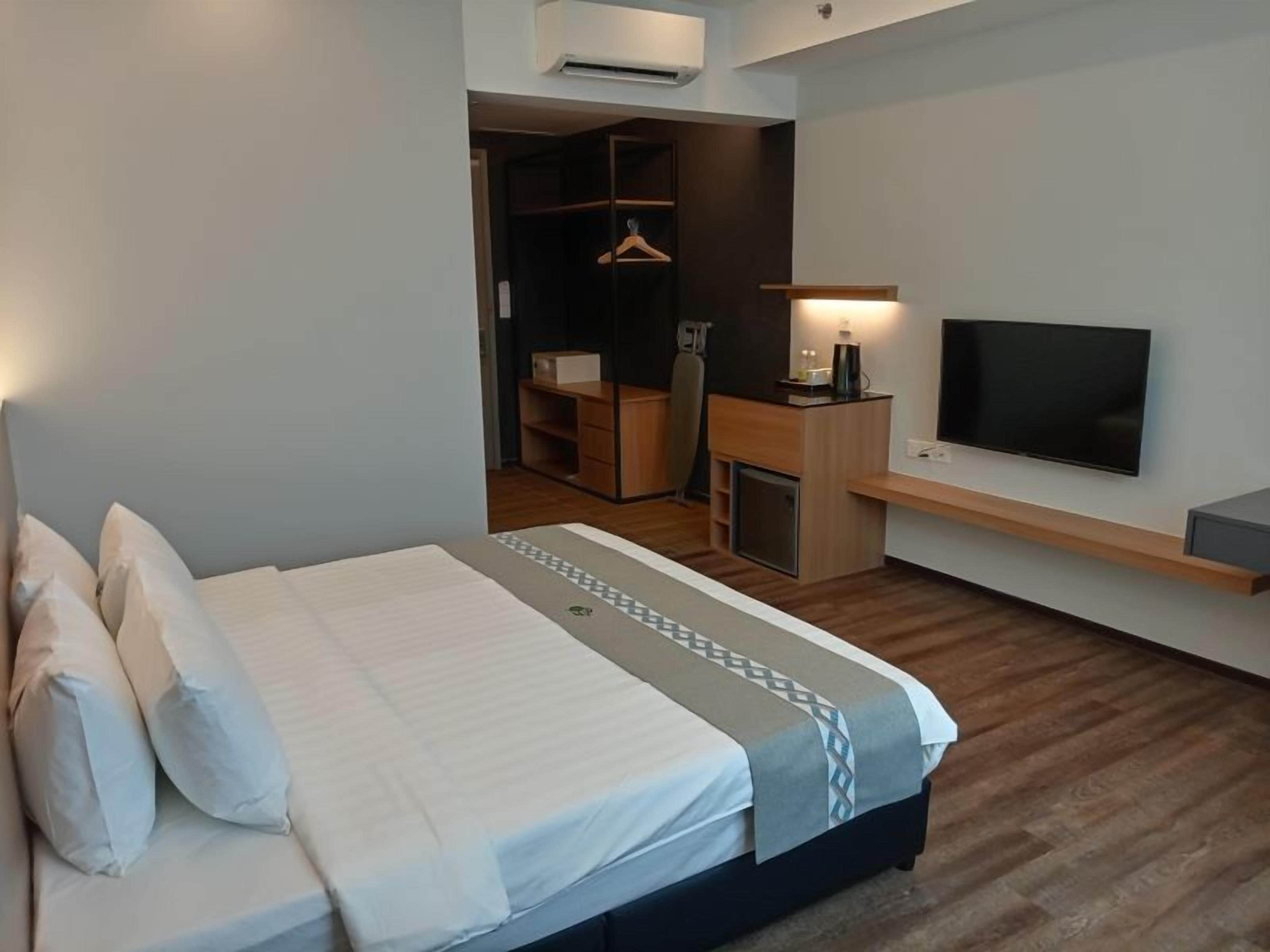Una habitación de hotel moderna con una cama, un televisor, un escritorio y un armario.