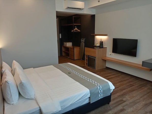 A modern hotel room with a bed, a TV, a desk, and a wardrobe. - 56 Hotel Block B (Kuching)