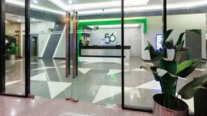 Uma área de recepção moderna com portas de vidro, balcão de atendimento e uma parede verde como destaque.