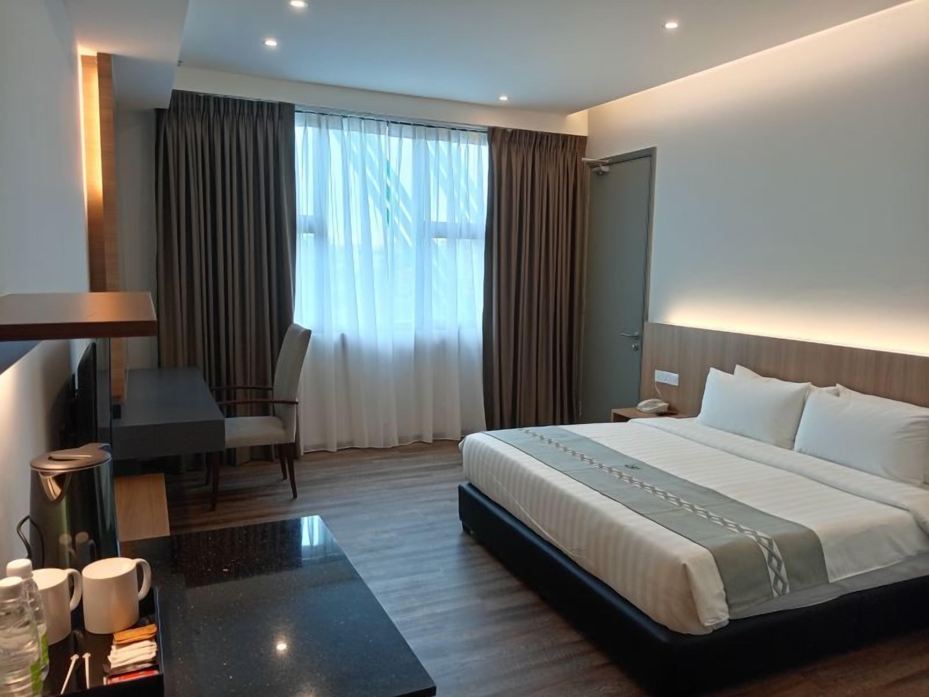 A modern hotel room with a large bed, a desk, and a chair.