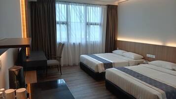 A hotel room with two beds, a desk, a chair, and a table with cups and a bottle.