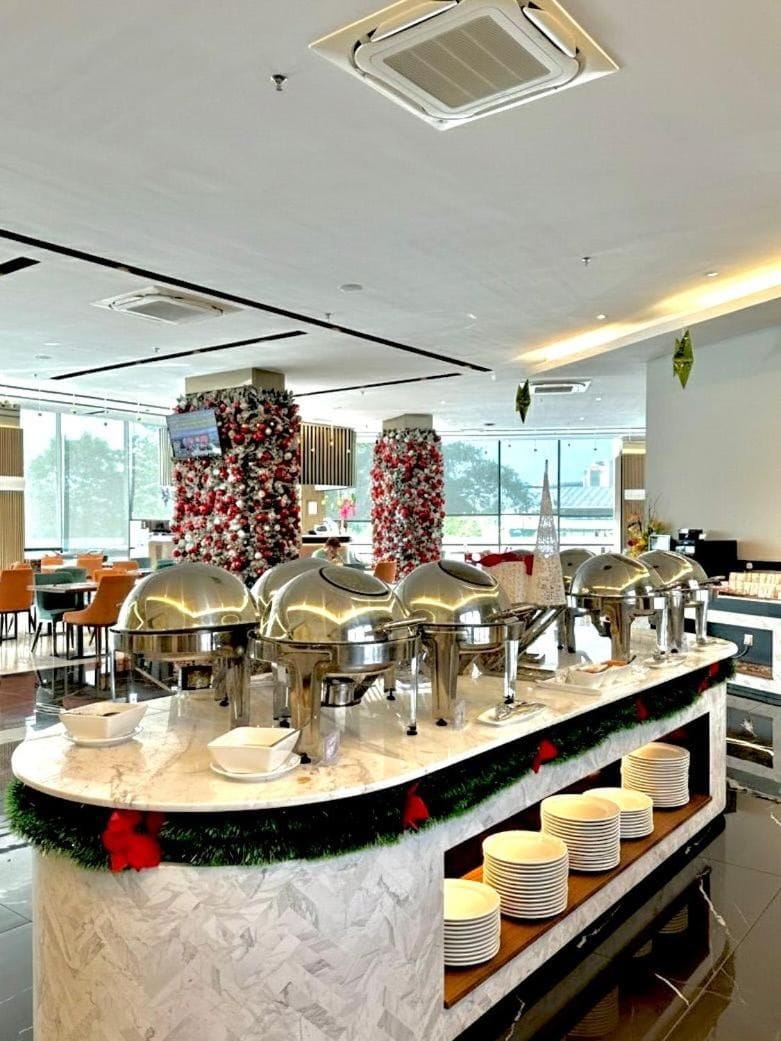 A buffet setup with multiple serving stations, a Christmas tree, and a modern interior design.