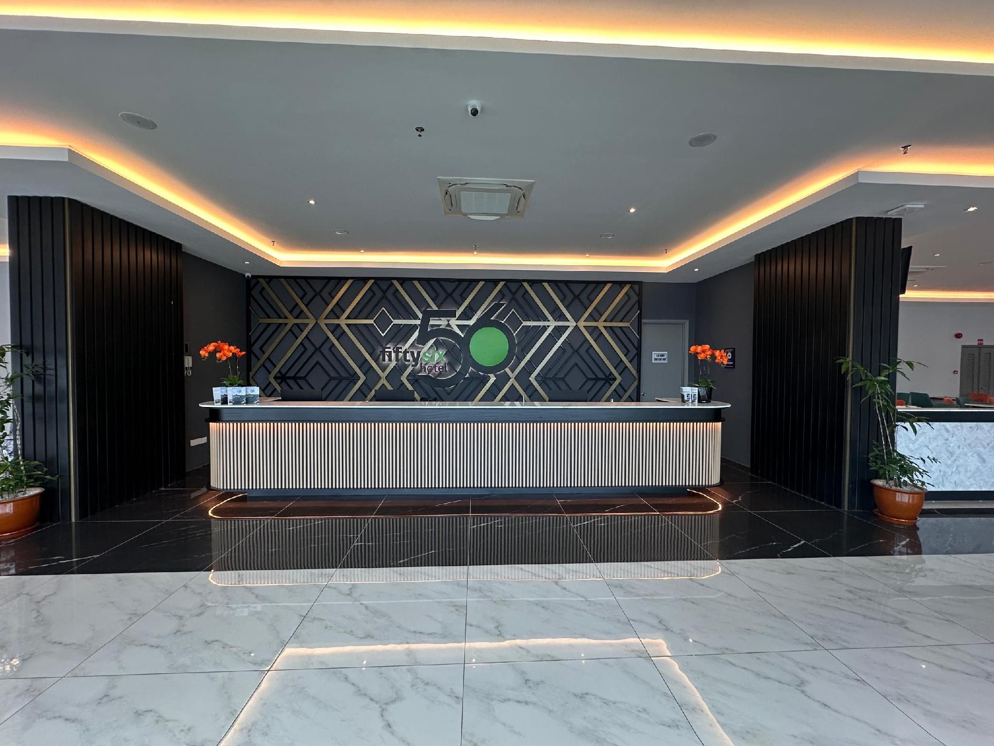 A hotel reception area with a modern design, featuring a reception desk, a geometric patterned wall, and a marble floor.