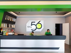 A reception desk with a large sign displaying '56 fifty hotel' and two individuals seated behind it. - 56 Hotel Block B (Kuching)