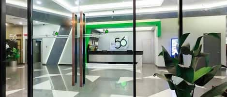 Un área de recepción moderna con puertas de vidrio, mostrador de recepción y una pared de acento verde.