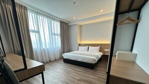Quarto de hotel com cama, mesa de cabeceira e escrivaninha com cadeira.