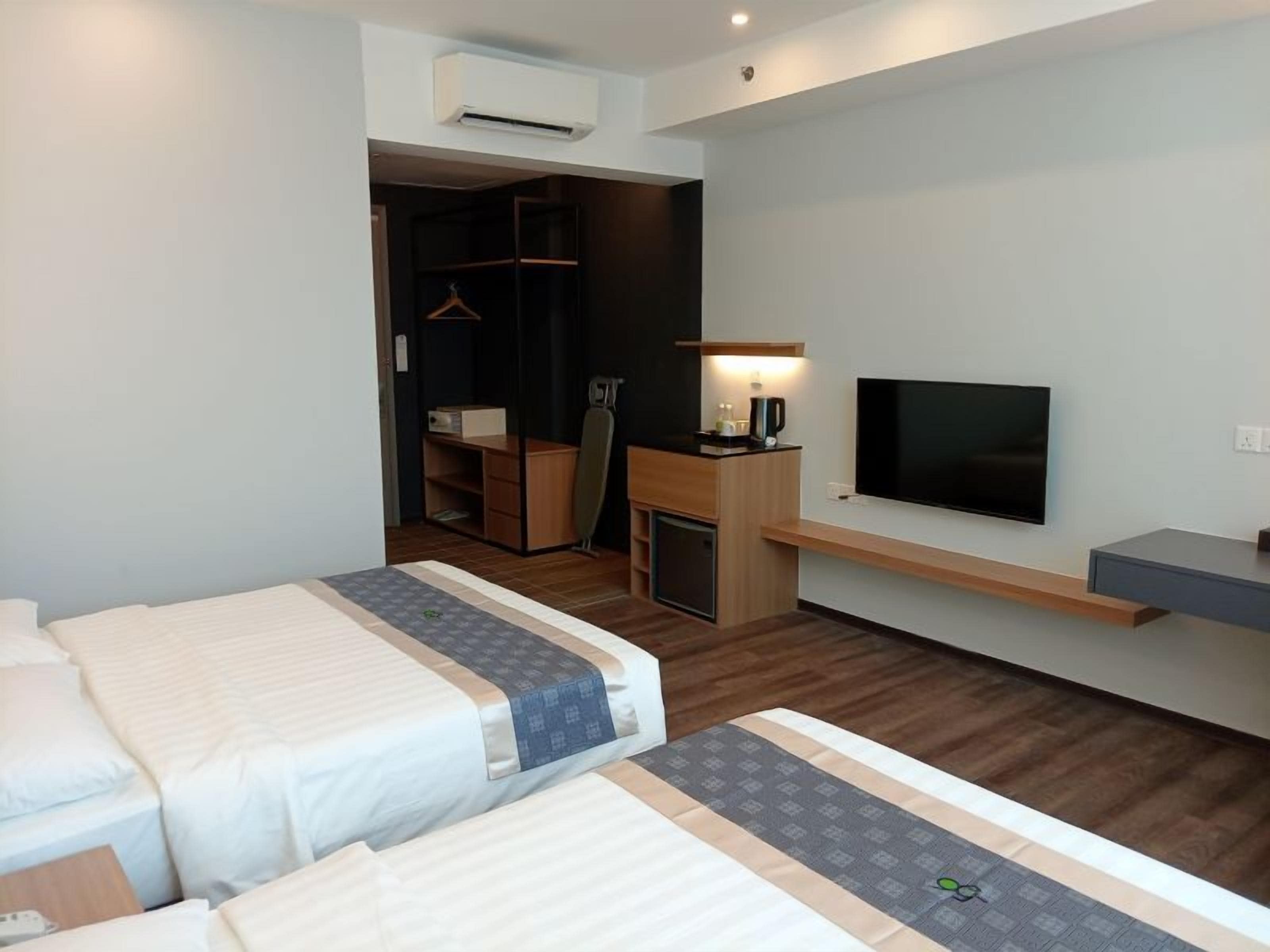 A hotel room with two beds, a desk, a TV, and a wardrobe.