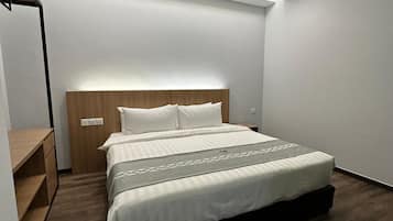 A modern bedroom with a large bed, a wooden headboard, and a built-in desk with drawers.