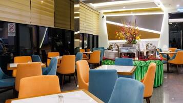 A restaurant with tables and chairs, a counter with a menu, and a flower arrangement.